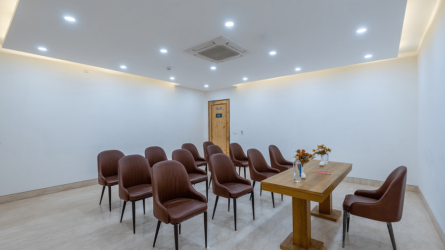  Front view of a conference room with a table placed between a chair and multiple chairs at DLS The Classio